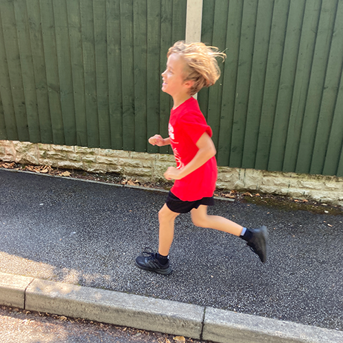 8 year old boy running past a fence
