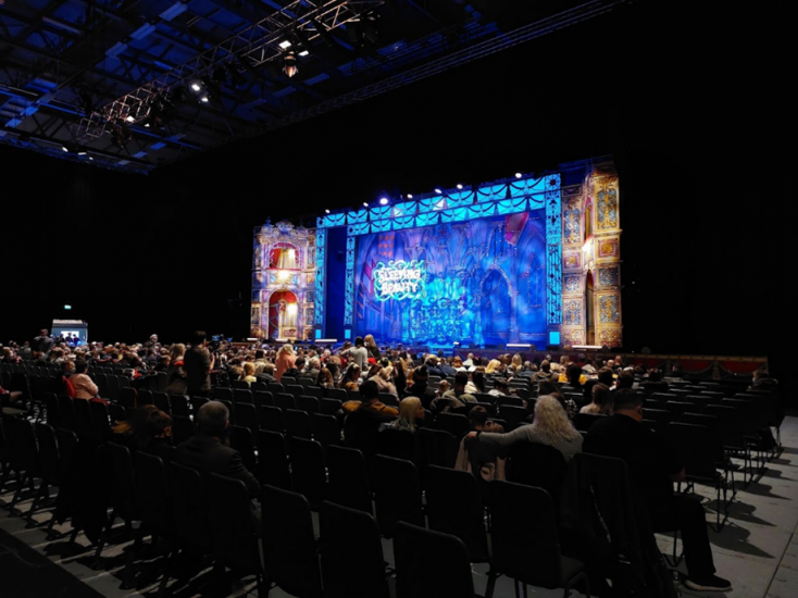 A stage with bright lights with rows of chairs in front.