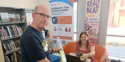 Visitor and volunteer in library pleased to be loaning and borrowing an item