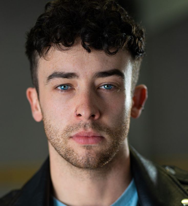 Actor Kristian Cunningham. He is a young man with dark, curly hair and blue eyes