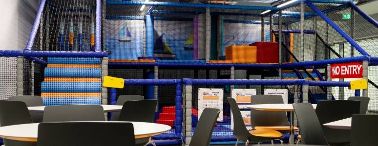 Tables and chairs in front of an enclosed soft play area