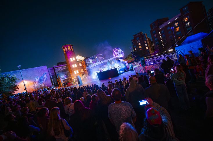A large light up structure with performers hanging underneath on wires