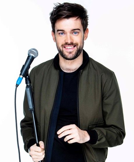 Jack Whitehall comedian stands with a mic.