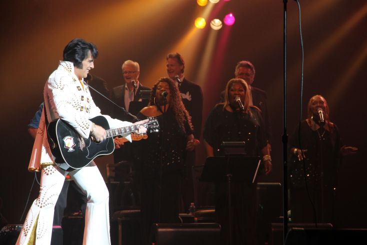 An Elvis tribute artist stands with guitar 