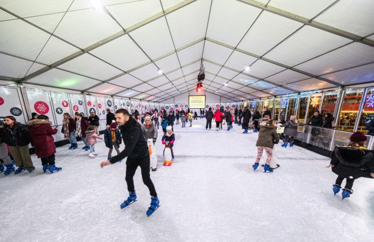 Children and families skate around on a indoor ice rink