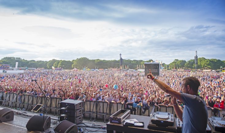 DJ Pat Sharp at an outdoor event on stage with the large crown in the audience behind him