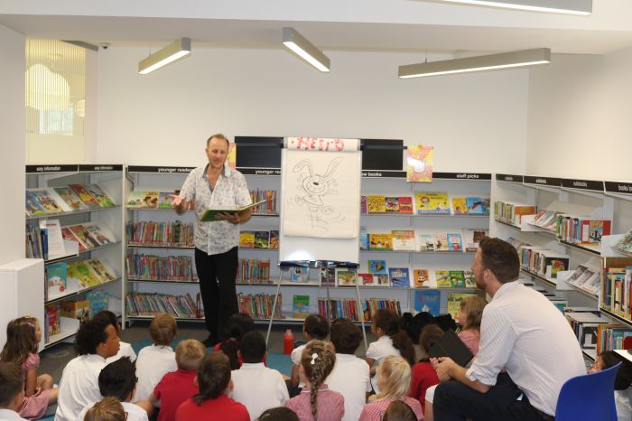 man standing at the front of library telling group of children a story