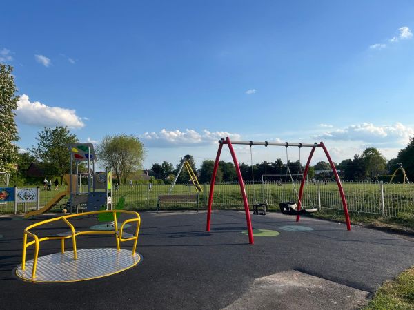 A park with a variety of park equipment, including as roundabout and swing that is accessible.